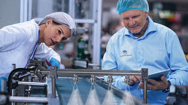 man and woman inspecting nozzle spray on conveyor