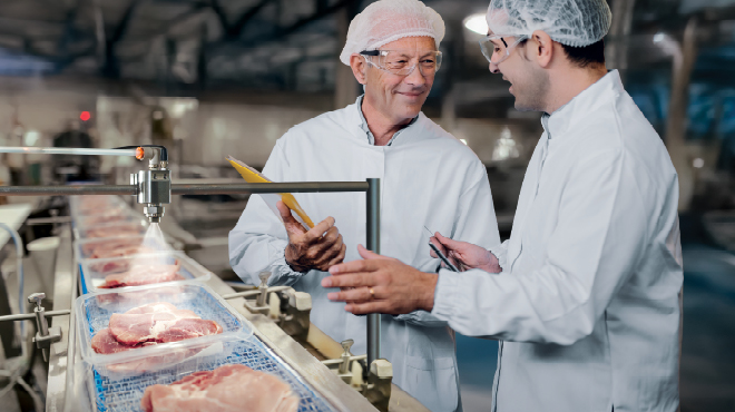 two men standing in meat processing plant