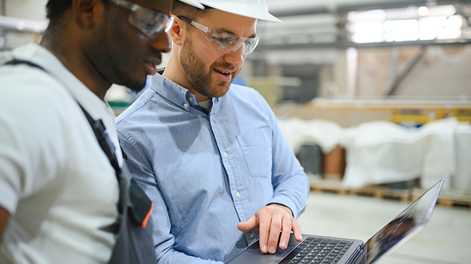 men looking at laptop in factory