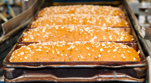 loaves of bread in pans on conveyor