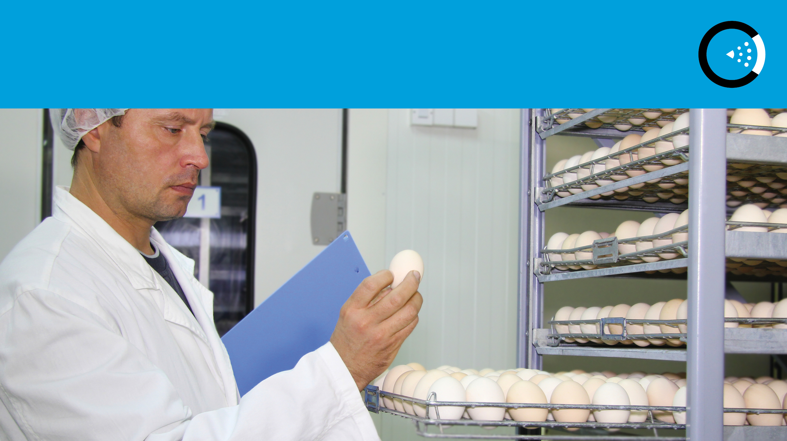 man in hairnet inspecting egg at a hatchery