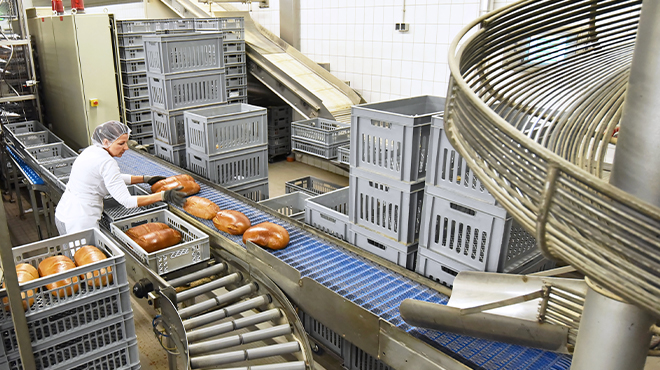 bakery worker placing loaves of bread onto conveyor