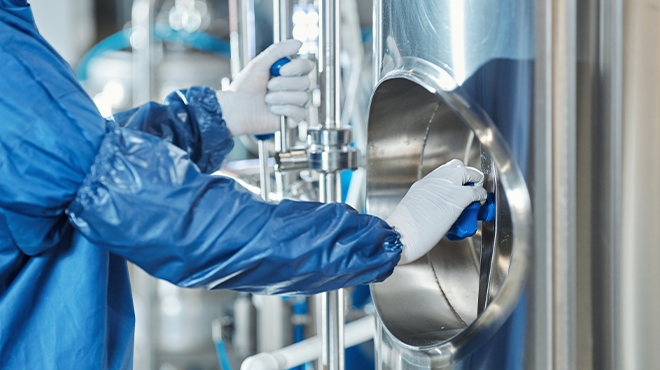 person in safety scrubs cleaning tank