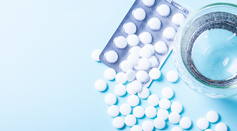 glass of water with a packet of pharmaceutical pills