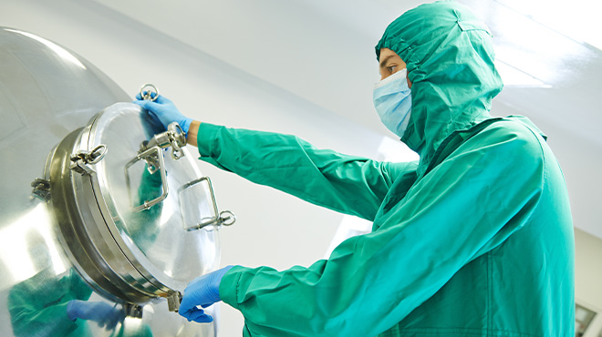 man in green scrubs with face mask opening tank