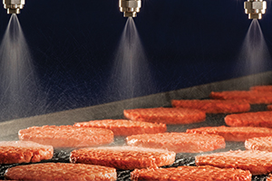 hamburgers being sprayed with antimicrobial on conveyor