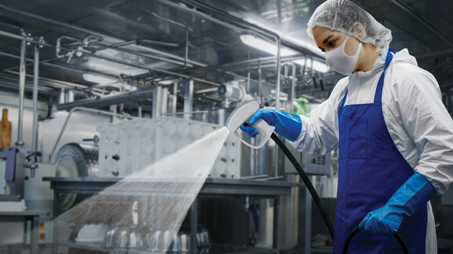 trident spray gun being sprayed by woman in hair net and mask