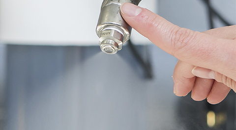 finger touching nozzle spraying water