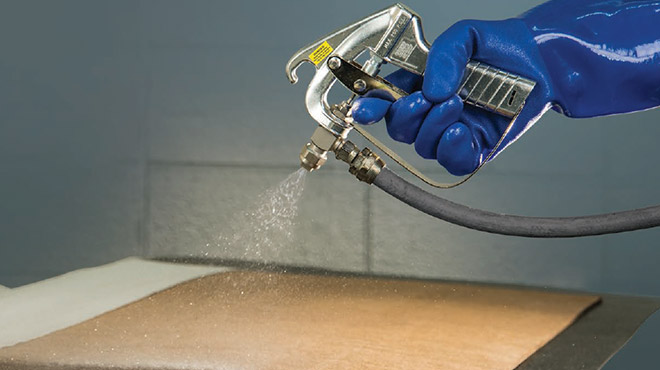 gloved hand holding a medium pressure spray gun spraying water