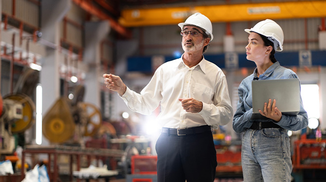 man and woman in hard hats standing in warehouse