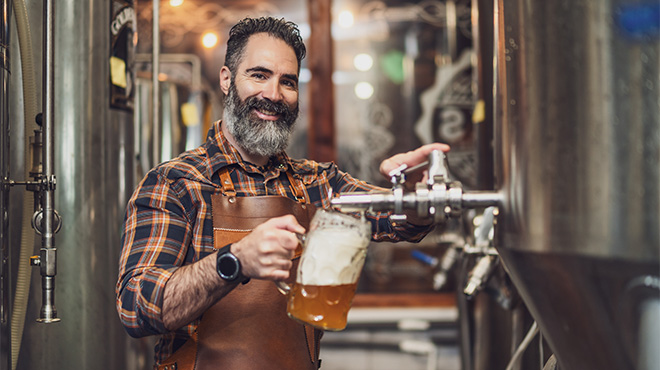 man filling a glass of beer from a tap